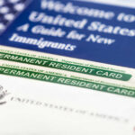 Massive Immigration Twist: Exits Before Entry U.S. permanent resident cards with immigration guide and flag