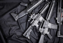 Spanberger’s Gun Ban IGNITES Legal Firestorm Black rifles on a dark fabric background