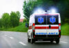 Ambulance driving on a road with flashing lights.