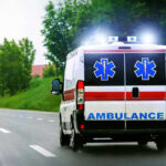 Ambulance driving on a road with flashing lights.