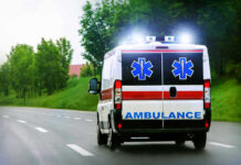 Ambulance driving on a road with flashing lights.