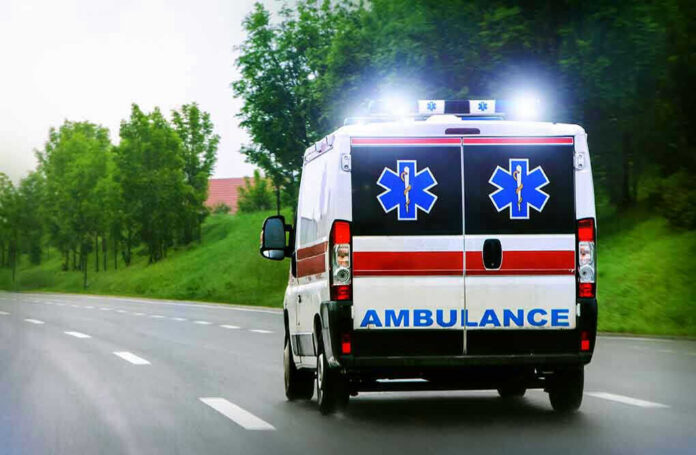 Ambulance driving on a road with flashing lights.