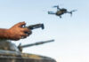 Hands holding a drone controller with quadcopter in flight