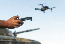 Hands holding a drone controller with quadcopter in flight