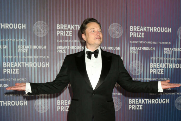 elon-musk-suit2449367659jpg-1 man in a tuxedo posing with arms outstretched at an awards event