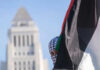 Person holding Palestinian flag near tall building