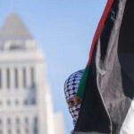 Person holding Palestinian flag near tall building