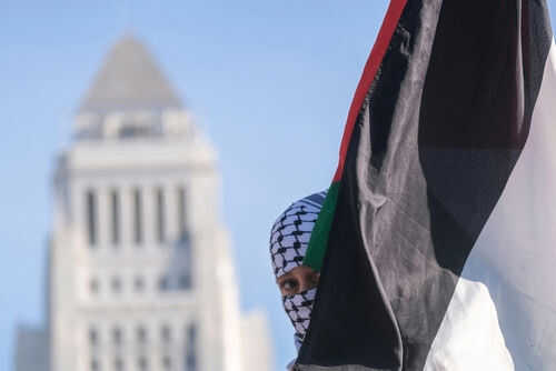 Person holding Palestinian flag near tall building
