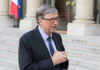 A man in a suit speaking outdoors near a building