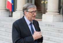 A man in a suit speaking outdoors near a building