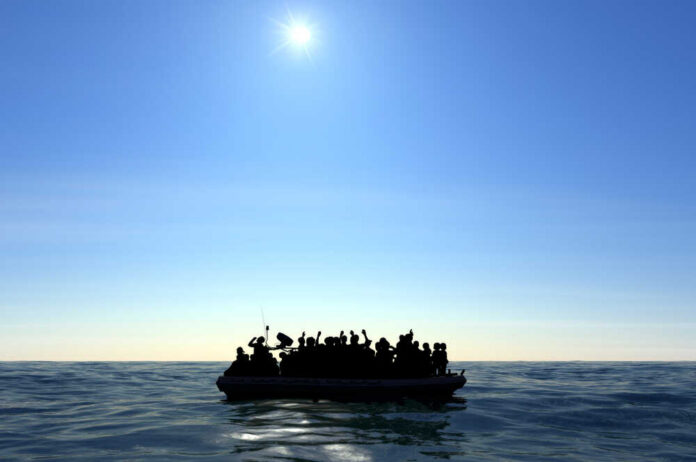 Silhouetted figures on a boat in the ocean under a bright sun