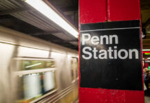 Commuters Stunned: Random Stabbings Strike Again Sign for Penn Station at a subway platform with a moving train in the background