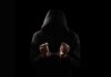 Felony Allegation Rocks Rams Locker Room A hooded figure with hands in handcuffs against a dark background
