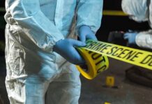 forensic investigators unrolling yellow barrier tape at night