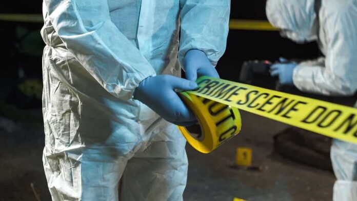 forensic investigators unrolling yellow barrier tape at night