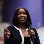 A woman speaking into a microphone with a smile