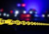 Police line tape with blurred emergency lights in the background