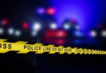 Police line tape with blurred emergency lights in the background