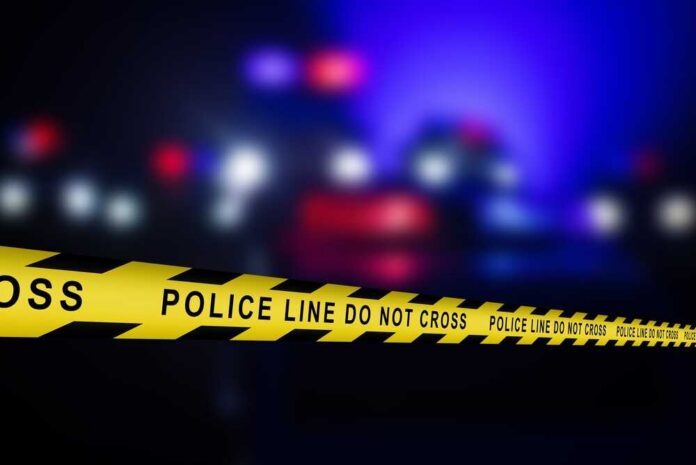 Police line tape with blurred emergency lights in the background