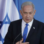Netanyahu Says The Buffer Zones Remain Man speaking in front of Israeli flag backdrop