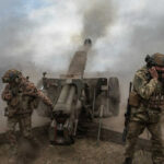 Army Eyes A New Generation Of Ammunition Soldiers fire a field howitzer as smoke and dust rise around them