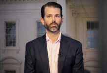 Man in a suit standing indoors with windows background