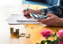 person using calculator with coins on table
