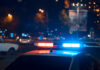 Police car with flashing blue and red lights in a city at night