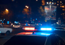 Police car with flashing blue and red lights in a city at night