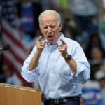 man speaking at a rally pointing toward the crowd