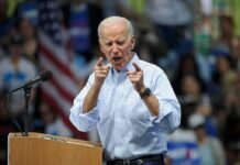 man speaking at a rally pointing toward the crowd