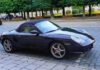 Black convertible sports car parked on cobblestone street