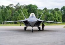 America’s Top Fighter Just Hit A Milestone F-22 Raptor military aircraft on the tarmac with a crew member performing maintenance