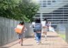 Children with backpacks running on a walkway toward a modern school building
