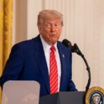 Trump Questions NATO’s Future After Summit A man in a suit speaking at a podium in a formal setting
