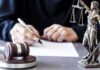 When Does Life Start? Courts Dodge Judge writing at desk with gavel and Lady Justice statue