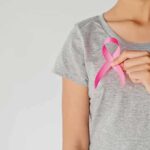 Person holding a pink ribbon on a gray shirt