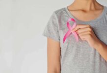 Person holding a pink ribbon on a gray shirt