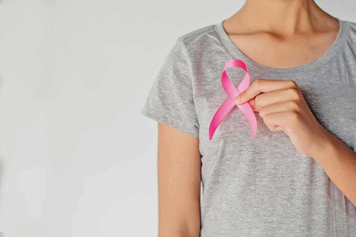 Person holding a pink ribbon on a gray shirt