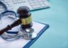 Gavel and stethoscope on medical clipboard near keyboard