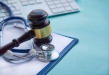 Gavel and stethoscope on medical clipboard near keyboard