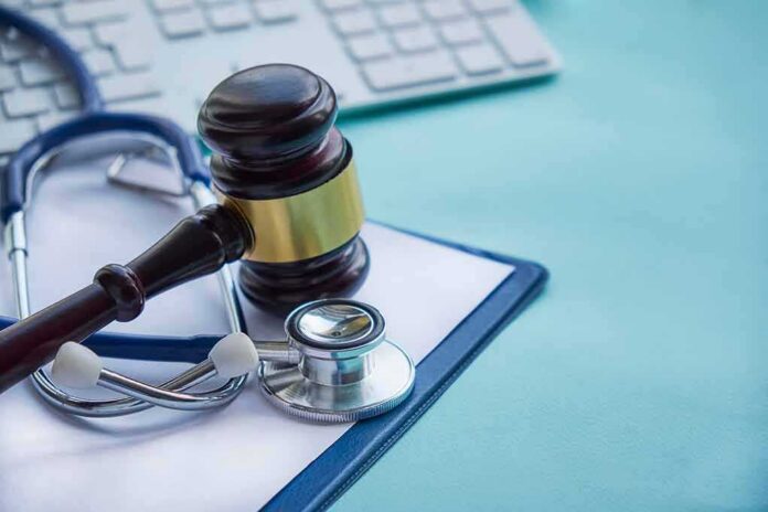 Gavel and stethoscope on medical clipboard near keyboard