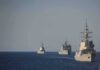Three naval warships sailing in formation on open sea