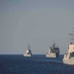 Three naval warships sailing in formation on open sea