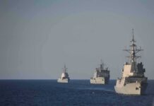 Three naval warships sailing in formation on open sea