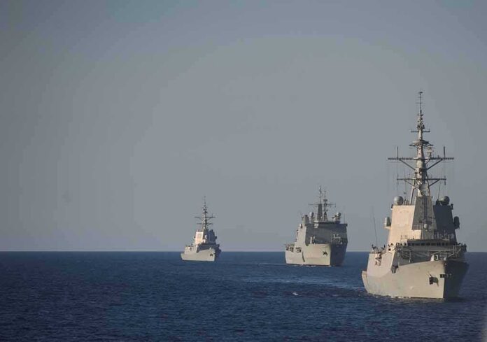 shutterstock_1119666839 Three naval warships sailing in formation on open sea