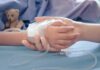 Child's hand with IV line held by another hand