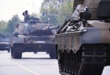 Military tanks drive down a city street