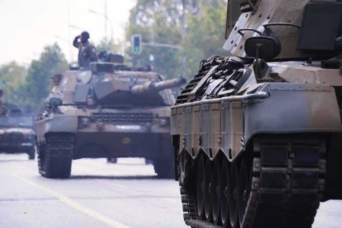Military tanks drive down a city street