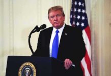 Trump’s Endorsement Faces a Crucial Tuesday Test man at podium with microphone and US flag
